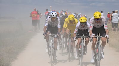 UAE Team Emirates rider Tadej Pogacar, in the overall leader's yellow jersey, follows his teammates on a gravel road. AP
