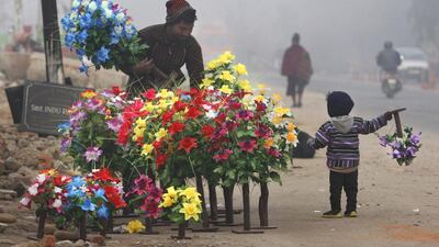 A boy helps his father set up his roadside flower stall in Jammu. Channi Anand / AP Photo