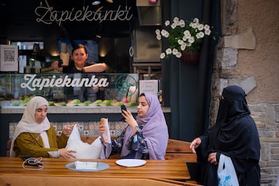 Tourists take a picture of a kebab on Krupowki, the main pedestrian zone of Zakopane, on August 4, 2025. Zakopane, located in southern Poland, has become a major summer destination for holidaymakers from the United Arab Emirates, Saudi Arabia and Kuwait, with as many as seven daily flights from the region at nearby Krakow Airport. (Photo by BARTOSZ SIEDLIK and Bartosz Siedlik / AFP) / TO GO WITH STORY BY STANISLAW NAKLICKI