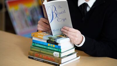 FILE - Amanda Darrow, director of youth, family and education programs at the Utah Pride Center, poses with books, including "The Bluest Eye," by Toni Morrison, that have been the subject of complaints from parents in Salt Lake City on Dec. 16, 2021. The wave of book bannings around the country has reached a level not seen for decades. (AP Photo / Rick Bowmer, File)