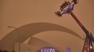 People ride on a fairground attraction in a cloud of red dust in Santa Cruz de Tenerife, Spain. AP Photo