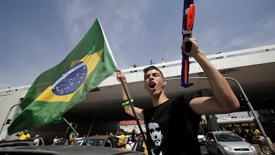 A demonstrator holds a toy gun and a Brazilian flag, during a race in support of Jair Bolsonaro, presidential candidate for the National Social Liberal Party. AP