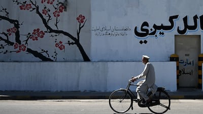 An Afghan man rides a bicycle past a barrier wall in Kabul. AFP