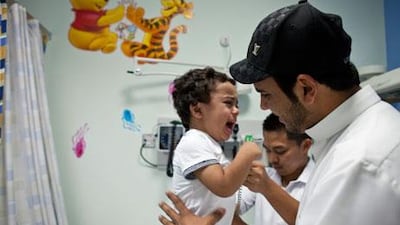 Abdullah Suhail holds his son Suhail, 2, during a paediatric check-up by nurse Raniel Arriesgado at Sheikh Khalifa General Hospital in Umm Al Quwain, where the little boy is receiving laser therapy for chronic bronchitis and sinusitis. The final phase of the 207-bed hospital will open in 2015. Razan Alzayani / The National