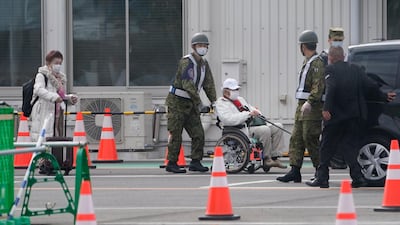 Passengers of the Diamond Princess cruise ship are helped by members of the Japan Self-Defense Force as they leave the Daikoku Pier Cruise Terminal in Yokohama. EPA