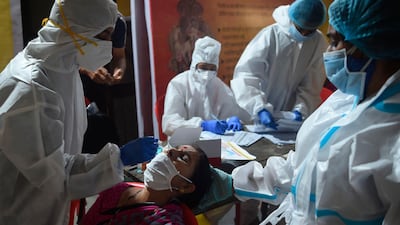 A health worker wearing protective gear collects a swab sample from a resident during a medical screening for the Covid-19 coronavirus at a police colony in Mumbai. India's total coronavirus cases passed five million on September 16, health ministry data showed, as the pandemic extends its grip on the vast country at an ever-faster rate. AFP