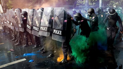 Riot police stand in formation as pro-democracy protesters throw smoke bombs near the Parliament in Bangkok. Thailand's political battleground shifted to the country's Parliament on Tuesday, where lawmakers are considering proposals to amend the country's constitution - one of the core demands of the student-led pro-democracy movement. AP Photo