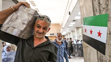 A man carrying Syrian pounds leaves the central bank in Damascus, in May 2025. Inflation is expected to rise. AFP