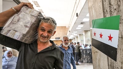 A man carrying Syrian pounds leaves the central bank in Damascus, in May 2025. Inflation is expected to rise. AFP