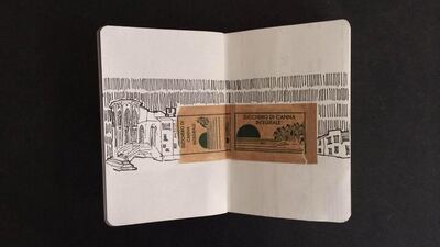 A sketchbook page with sugar packet wrapper and a drawing of houses by a bridge. (Courtesy: Bassant Elshimy)