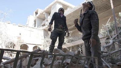 Syrian rescue workers look up to the sky in search of warplanes above Aleppo. Karam Al Masri / AFP