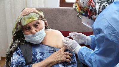 In this photo provided by Turkey's Health Ministry, a vaccination team member administers a dose of the CoronaVac vaccine, produced by China's Sinovac Biotech Ltd., to Sati Kayiran, 88, in Ayas, in Ankara province, Turkey, Thursday, Jan. 21, 2021. Turkey on Thursday expanded its COVID-19 inoculation campaign to include people aged 85 and older. (Turkish Health Ministry via AP)