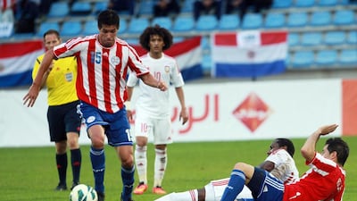 Paraguay's Victor Caceres, left, tries to race away as the UAE's Khamis Ismail slides in for a challenge during their friendly at Villach, Austria, on September 7, 2014. DANIEL RAUNIG / AFP
