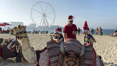 American expatriates Matt Hubbard with his children Olivia, 8, left and Gage,10, with a camel on the JBR beach on Christmas Day. Christopher Pike / The National