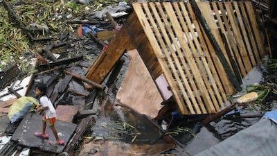 A Filipina child stands on debris after heavy rains swept in a barge which damaged shanties in Manila.