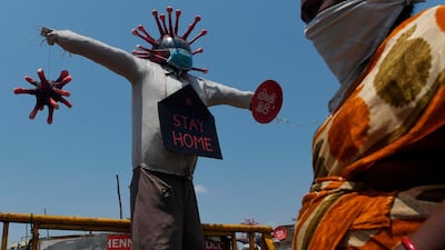 A woman walks past a coronavirus awareness scarecrow installed by municipality of Chennai city in southern India on April 11, 2020. AFP