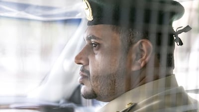 First Lieutenant Essa Ahmed sits in a patrol car.