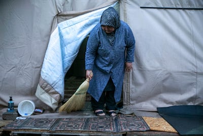 A woman sweeps the entrance to the tent in which her family are living having been displaced, in Kahramanmaras, Turkey. AP