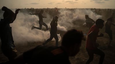 Palestinian protesters kick back teargas fired by Israeli troops during a protest at the Gaza Strip's border with Israel, east of Gaza Cit. AP Photo