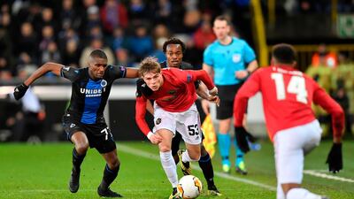 Manchester United's Brandon Williams, centre, is challenged by Club Brugge's Clinton Mata, left. AFP