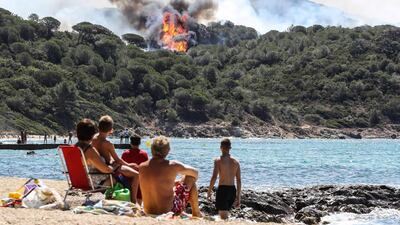 Beachgoers watch a forest fire from afar in La Croix-Valmer, near Saint-Tropez, France. Valery Hache / AFP Photo / July 25, 2017
