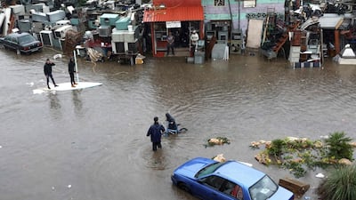 Lebanese men use a paddle board to help a youth pushing a bicycle as he wades through the water on a flooded road due to heavy rain, at the southern entrance of the capital Beirut. AFP