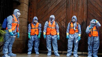 Municipal workers wearing personal protective equipment wait to enter the residence of Bollywood actor Amitabh Bachchan to sanitise it after he and his son, actor Abhishek Bachchan, tested positive for the coronavirus, in Mumbai, India. Reuters