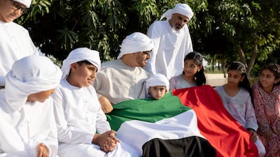 Sheikh Mohamed with his grandchildren and the UAE flag. Ryan Carter / UAE Presidential Court