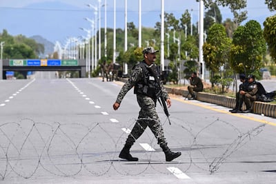 A Pakistani Ranger walks past barbed wire spread over a road near the expected venue of the US-Iran talks in the Red Zone area of Islamabad. AFP