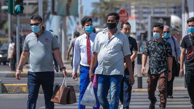 Residents wearing face masks cross Zayed The First Street in central Abu Dhabi. Victor Besa / The National