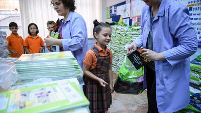 A teacher gives a school child a booklet entitled 'In memory of July 15, the Martyrs and the Victory of Democracy' as she collects her school books during the first day back at school on September 19, 2016 in Istanbul. AFP