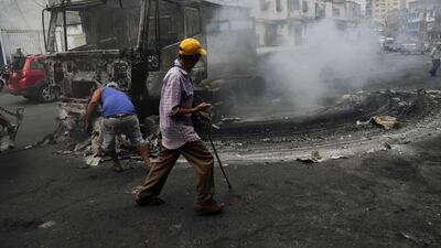 Workers use a crane to move the wreckage of a truck that was burned down during protests in Caracas. AFP