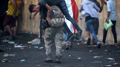 An Iraqi protester carry away a wounded comrade amid clashes with security forces at Baghdad's Khallani square during ongoing anti-government demonstrations. AFP