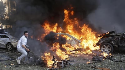 A Lebanese man tries to pull a body out of a burned car. Hussein Malla / AP Photo
