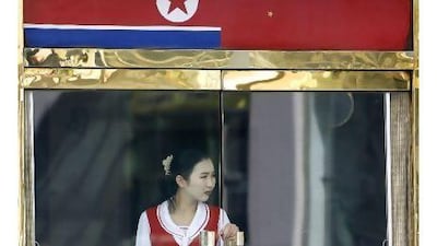 A North Korean waitress stands under the China and North Korean flags at a restaurant in the Chinese border city of Dandong. A reader notes that China is keeping North Korea's antiquated regime in power. AFP / LIU Jin