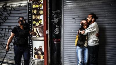 A man protects a woman as they face a police officer dispersing protesters gathering on the central Istoklal Avenue near Taksim square in Istanbul on Saturday. Bulent Kilic / AFP