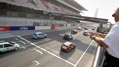 Cars roar past the starting line during the last race of the UAE National Race Day at Dubai Autodrome.