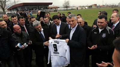 Kosovo prime minister Hashim Thaci, centre right, holds up the national team jersey bearing his name during a training session by the team. Visar Kryeziu / AP