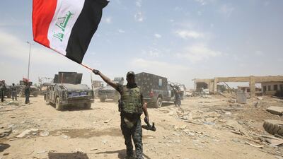 An Iraqi federal police member waves his country's national flag in celebration in the Old City of Mosul on July 8, 2017, as their part of the battle has been declared accomplished, while other forces continue to fight Islamic State (IS) jihadists in the city. / AFP PHOTO / AHMAD AL-RUBAYE