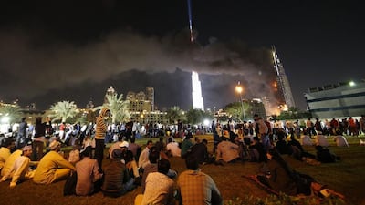 People watch the Address Downtown hotel burning after huge fire ripped through the luxury hotel near the world’s tallest tower, in Dubai. People were gathering to watch New Year’s Eve celebrations when the hotel caught on fire without causing casualties, according to authorities. Karim Sahib / AFP Photo