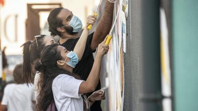 Visitors help paint an eL Seed Mural at Alserkal Avenue. Antonie Robertson / The National