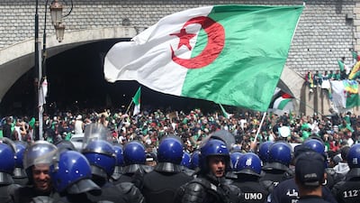 Algerian protesters wave a national flag as security forces stand guard during an an anti-government demonstration in Algiers on April 12, 2019. AFP