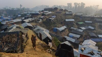 A Rohingya refugee woman walks with a child in her lap in Balukhali refugee camp in the Bangladeshi district of Ukhia. An estimated 618,000 Muslim Rohingya have fled mainly Buddhist Myanmar since a military crackdown was launched in Rakhine in August triggered an exodus, straining resources in the impoverished country. Munir Uz Zaman /AFP