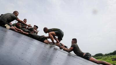 Participants help each other climb over an obstacle during the Tough Mudder event in Alabang, south of Manila, Philippines. Mark R. Cristino/EPA
