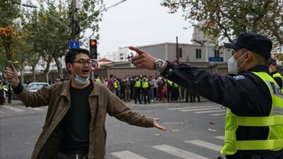 A protester holding flowers is confronted by a policeman during a protest on a street in Shanghai, China. AP