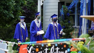 Bishop O'Connell High School graduates Michael Gallo, Daniel Cahill and Rafael Ruiz process during a front yard drive-in coronavirus honorary graduation ceremony at a home in Falls Church, Virginia, US. Reuters