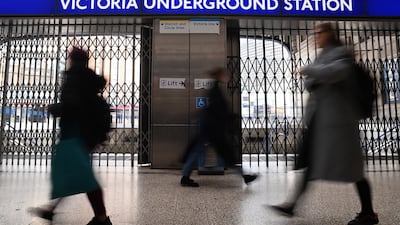 Commuters pass a closed Victoria Underground station in London. EPA