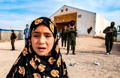 Kurdish fighters stand guard as a Syrian child, suspected of being related to Islamic State (IS) group fighters, waits at the Kurdish-run Al Hol Camp, before being released along with women and children to return to their homes, in the Al Hasakeh governorate in northeastern Syria, on October 28. AFP