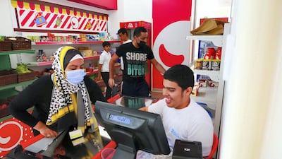 Omar Al Suwaidan , right, practices work as a cashier at the mock Zoom supermarket located in Sanad Village in Dubai Sustainable City. Photos by Pawan Singh / The National