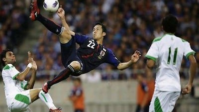 Japan's Maya Yoshida, centre, shoots the ball between Iraq's Waleed Salim, left, and Amjed Radhi Yousuf Al-Janabi.